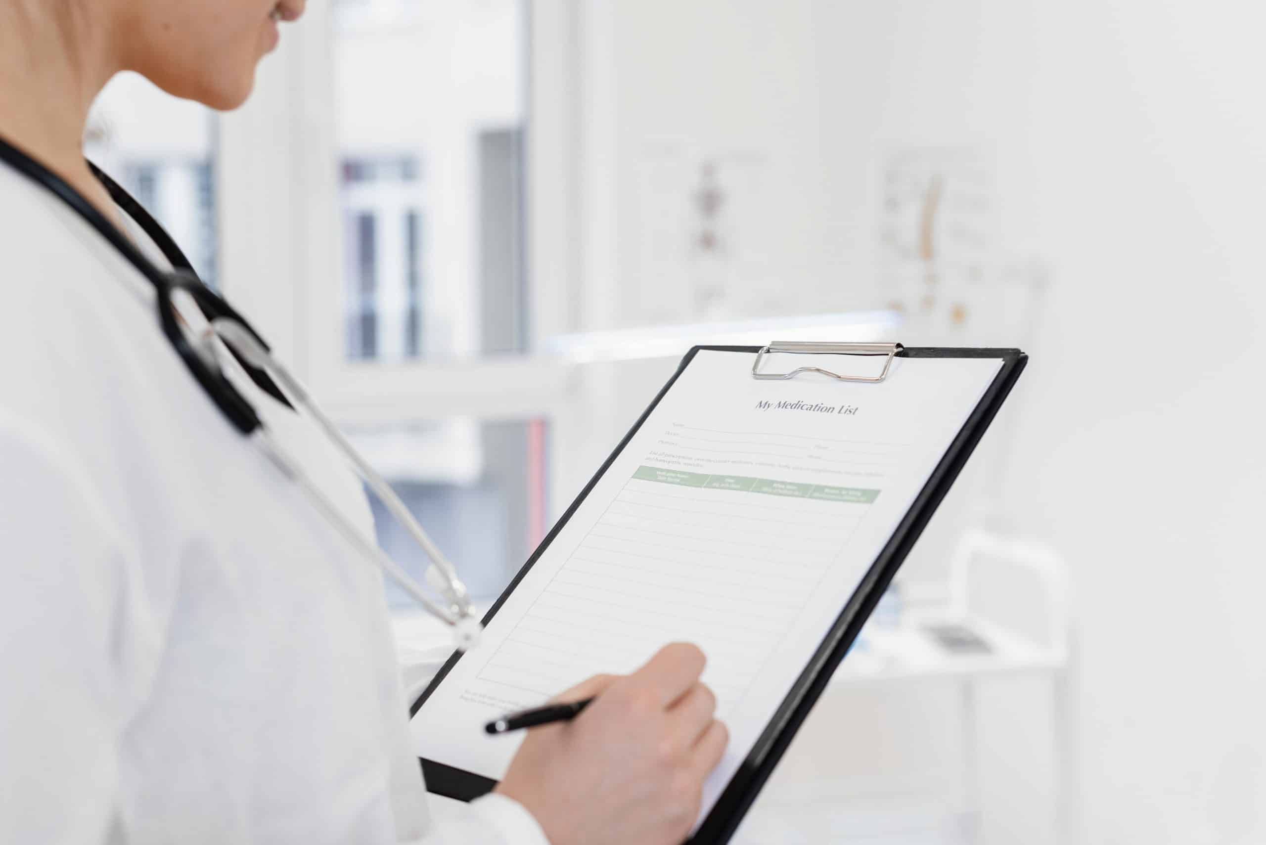 Close-up of doctor writing patient information on clipboard