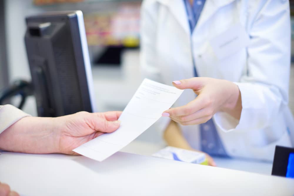 Close-up of patient's hands holding a prescription paper with medical instructions