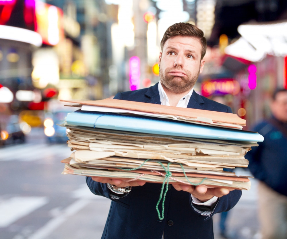 Man handing over a large stack of files and paperwork