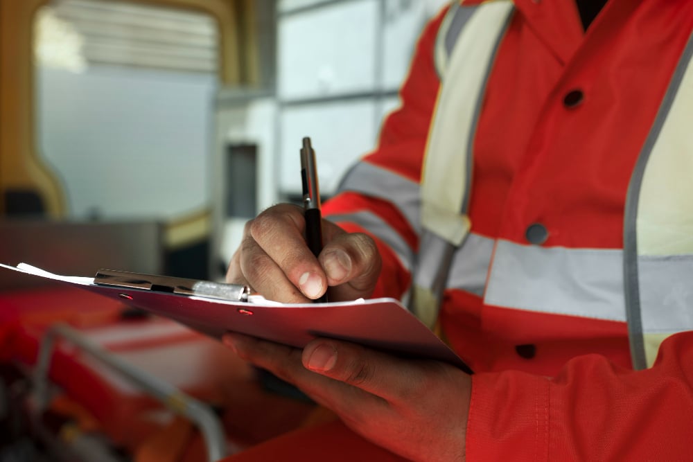 Paramedic writing patient notes in moving ambulance - side view