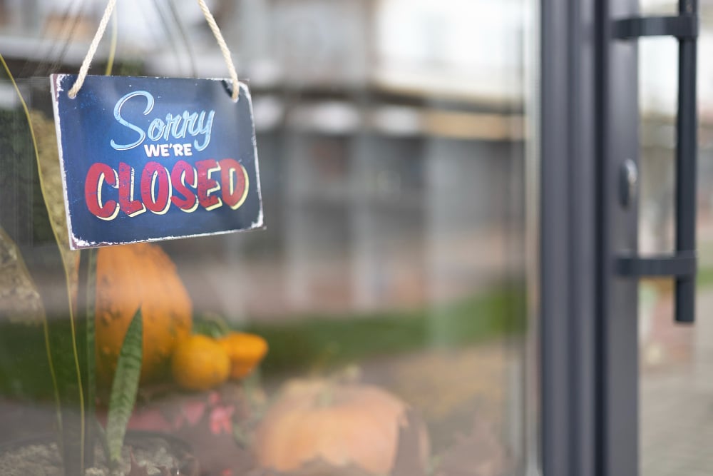 "Sorry We're Closed" sign hanging on door of retail store or business entrance