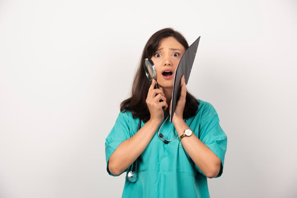 Confident female doctor with stethoscope and clipboard on white background