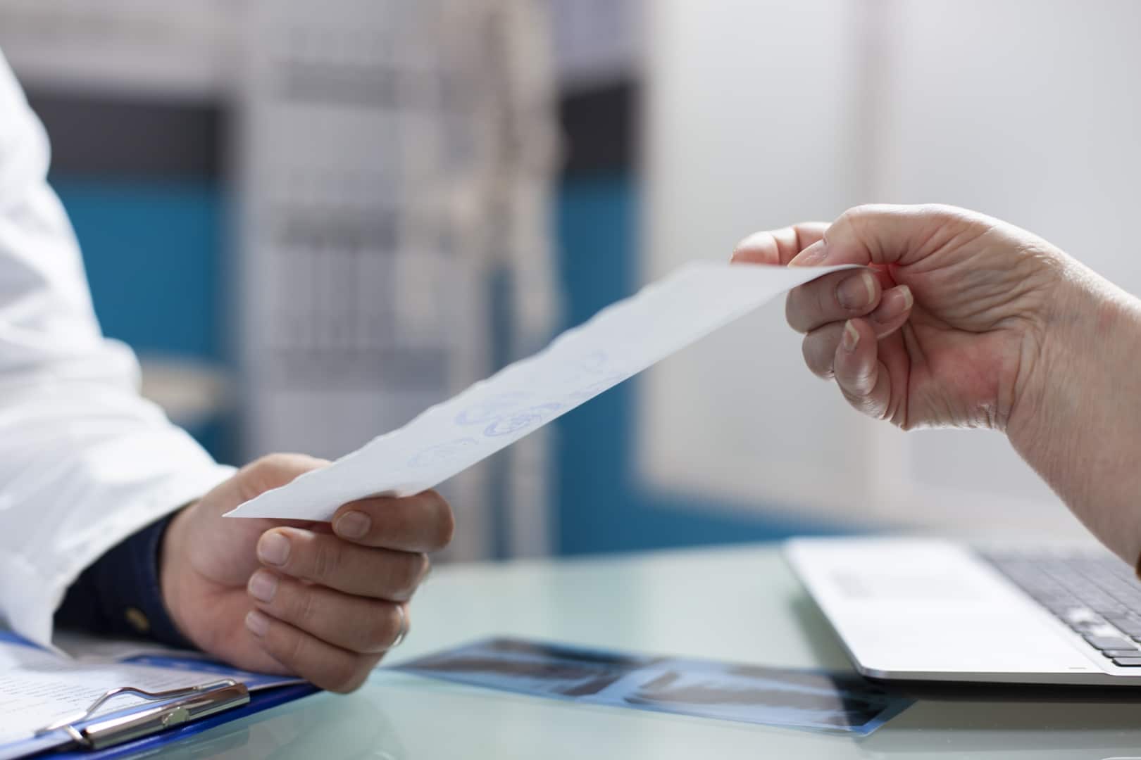Doctor handing a medical document to a patient inside a clinic office.
