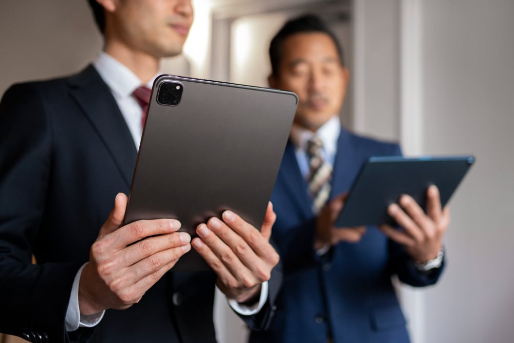 Two young men using digital tablets to access their files.