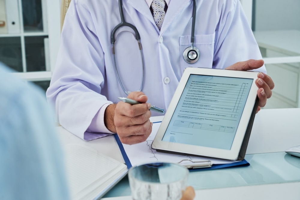 unrecognizable doctor extending the digital tab for anonymous patient to fill