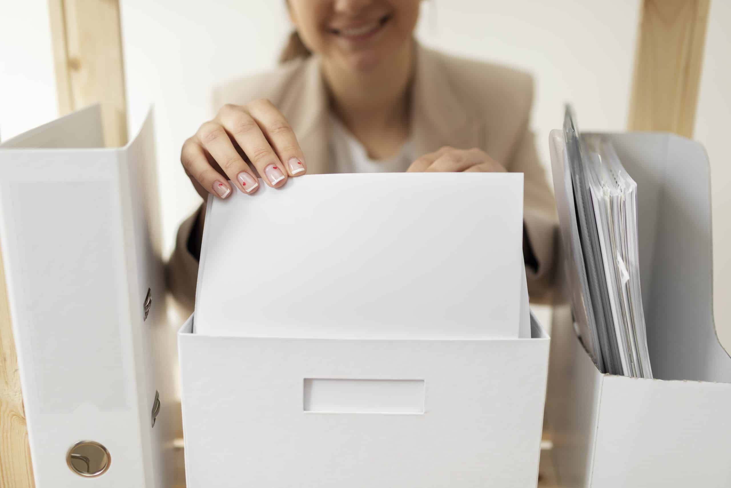 Smiling woman organizing file documents at desk