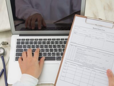 Top-view-of-doctor-using-a-laptop-and-a-clipboard-1536x1024